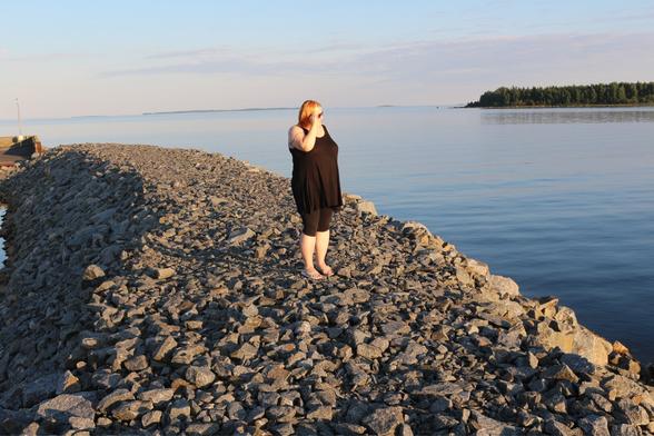 Woman standing on a rocky beach, sea, a  sea on the background.