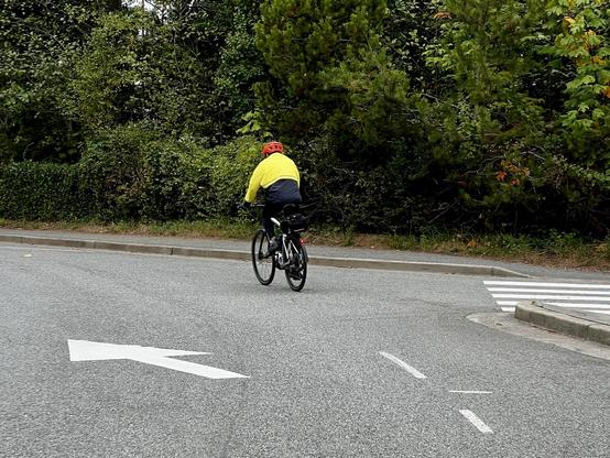 Single cyclist approaches a left turn on a paved road.