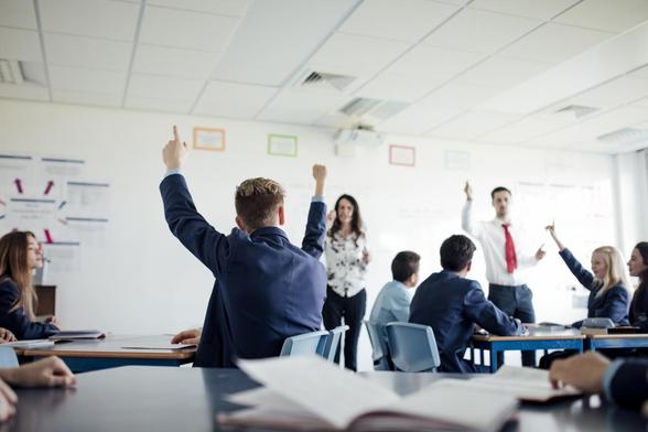 Teenage female student raising her hand to answer a question. (DEAN HINDMARCH)