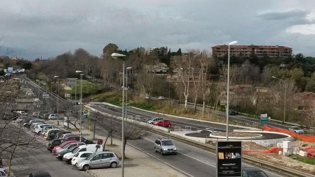 Parcheggio di scambio vuoto e recintato presso la stazione Casal Bernocchi della Roma-Lido, visibilmente completo ma senza illuminazione