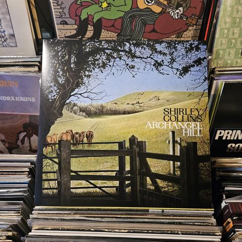 Album cover features a color illustration of a green hilly pasture beyond a pedestrian gate, with trees in the distance. Four horses are walking up the pasture.