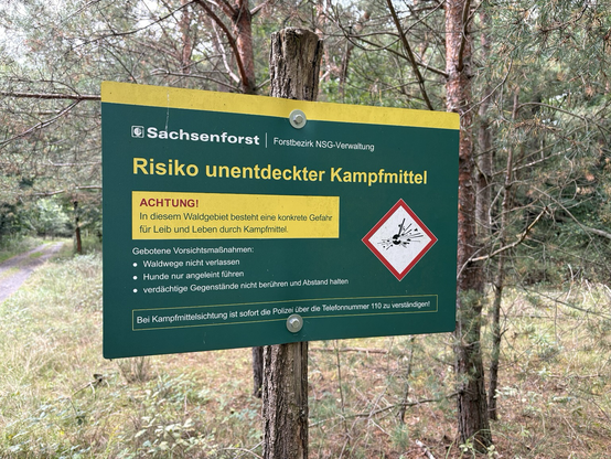 A sign depicting the risk of unexploded ordnance advising you not to leave the trail