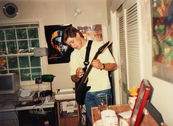 Teen (me) playing guitar in bedroom with Amiga 2000 computer and videogame posters in background