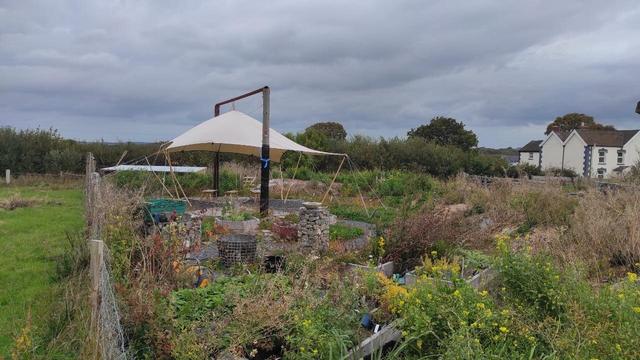 New garden with canvas shelter supported between 2 telegraph poles