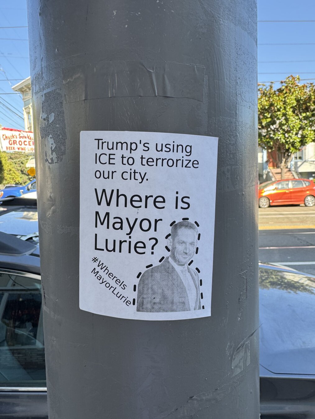 A white sticker on a street post. The sticker says "Trump's using ICE to terrorize our city. Where is Mayor Lurie? #WhereIsMayorLurie" and it has a photo of Daniel Lurie with dotted lines drawn around him, as if you can cut out the image.