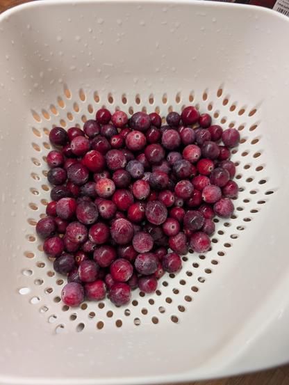 200g reife Cranberries in einem weißen Kunststoffsieb zum abtropfen nach dem Waschen.