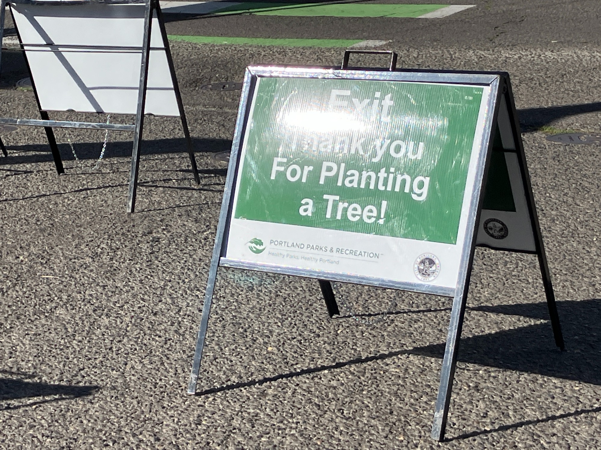 A green sign from the City of Portland noting the exit from it's tree giveaway event, thanking participants for planting a tree.