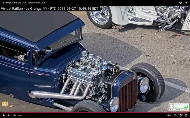 Ein alter dunkler Hot Rod, in der Frontschnautze ein großer silberglänzender Motor mit groem Auspuff
Im Hintergrund ein weißer Dreirad-Chopper - wird im anderen Bild genauer gezeigt

Das Fahrzeug steht in La Grange - Kentucky - USA auf einer Straße mit einer Schiene, auf welcher sporadisch lange Güterzüge fahren.
Dort findet ab und zu ein Treffen aufgearbeiteter alter Fahrzeuge statt