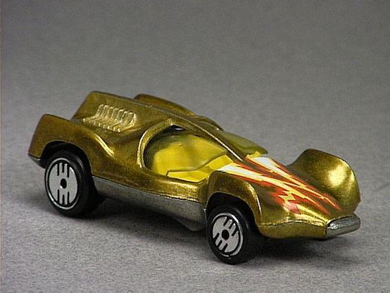 Released in 1985, Metal Flake Gold Speed Seeker of 1985 Hot Wheels with Ultra Hot wheels. Notes: Concept car with two yellow tinted movable plastic canopies. Tampo: Red, yellow and white lightning bolt in the front. Packaging: Ultra Hots Stamper 3 Pack. Metal Body, Metal Base. Made in Malaysia. Scarcity: 7/10
