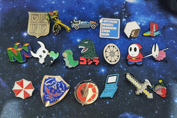Pins from Zelda, Nintendo and PlayStation logos, Final Fantasy menu, Minecraft, The Umbrella Corporation, a GBA SP, the Bash logo, Hornet, Hollow Knight, a Grub, Metroid logo, Samus, Godzilla, Kirby, the White Lotus from Avatar