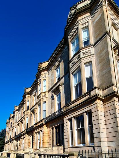 A terrace of blonde sandstone Italianate style Victorian townhouses.