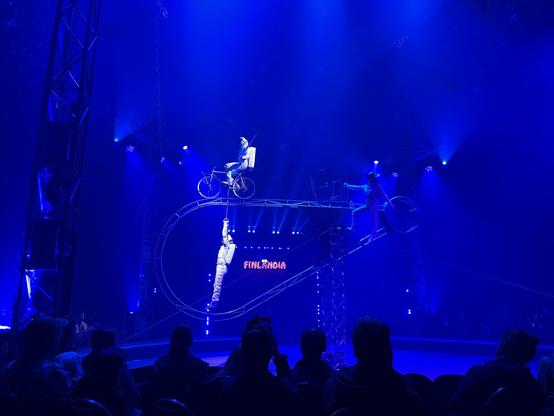 Ensimmäinen kuva jossa pyöräilijä tasapainoilee pisaran muotoisen metallirakenteen päällä, kun toinen roikkuu pyörän polkimien kohdalle kiinnitetyistä, lapion varsien näköisistä kahvoista sen alapuolella.

Telineen isompi osa kaareutuu vasemmalle ja pisaran kärki on oikealla.