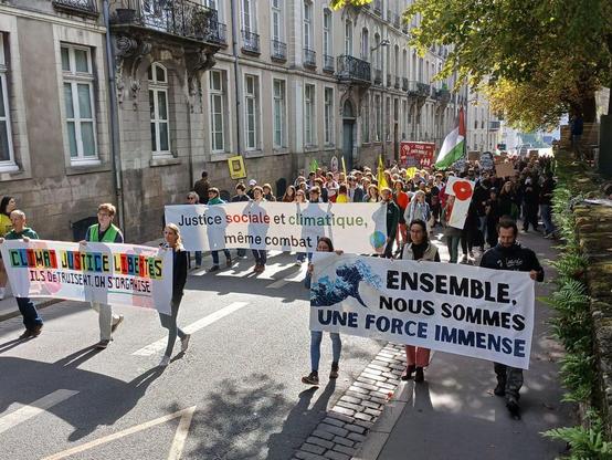 Groupes de personnes portant des banderoles sur la justice, le climat et la liberté.