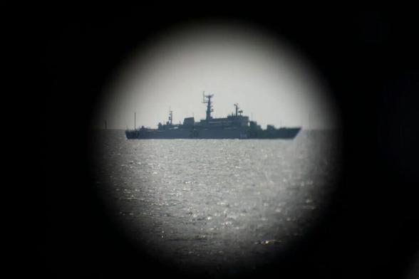 A Russian Navy ship is pictured through binoculars as it passes near the German Navy Frigate Sachsen, summer 2022, Baltic Sea