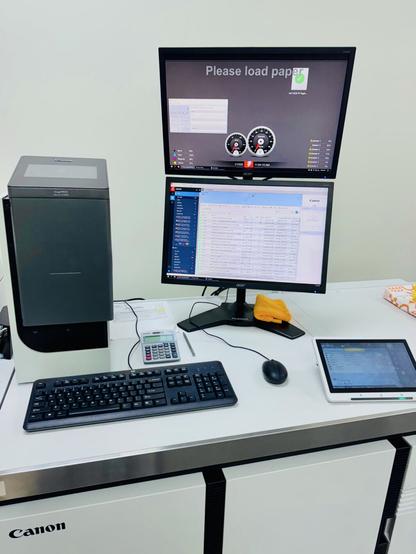 A computer system on top of a production digital copier running Fiery job management software in a stacked dual monitor configuration.