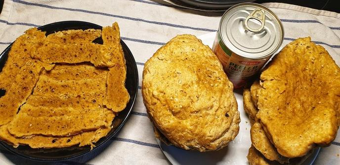 6 large pieces of seitan on a plate, with a can of tomatoes behind them to give an idea of size.  One of the slices cut into 'cutlets' for dinner tonight.