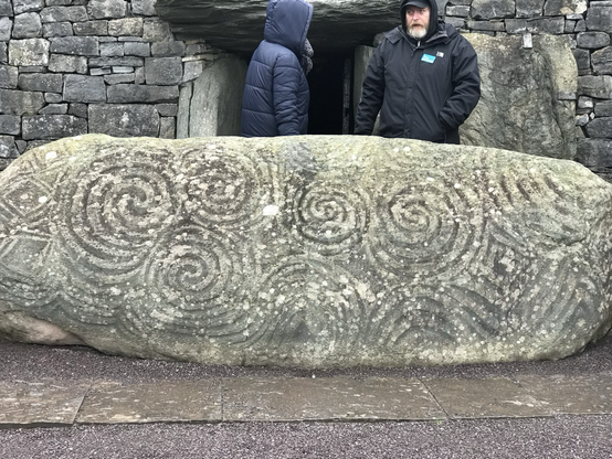 Close up of a large grey standing stone lying down.  It has beautiful spirals engraved on it.