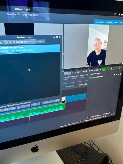 An image of a computer screen displaying a video editing software interface. There are editing timelines and a video preview showing a smiling individual with glasses. The screen includes various tools and options for editing audio and video projects.