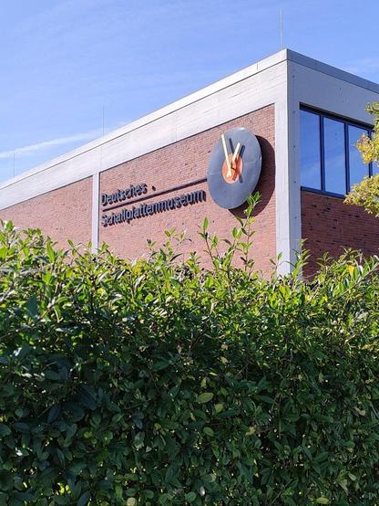 Außenansicht des Gebäudes. Neben dem Schriftzug "Deutsches Schallplattenmuseum" hängt eine große Uhr im Schallplattendesign.