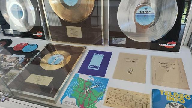 Eine Vitrine mit Druckstücken aus dem TELDEC-Betrieb und "goldenen" Schallplatten. Ein Flyer zeigt die Lage von Nortorf quasi im Zentrum Schleswig-Holsteins.