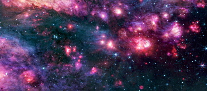 Mid-infrared view of Sagittarius B2, a dense and colorful star-forming region near the Milky Way’s center. The image shows clouds of gas and dust glowing in shades of pink, red, and purple with many blue and white stars scattered throughout the dark background.