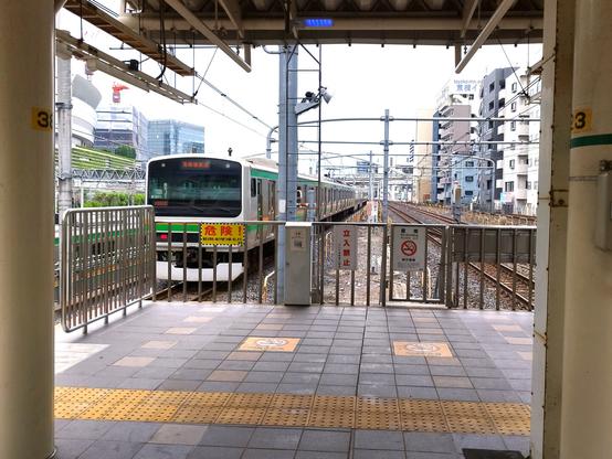 A commuter train has just left the station. The shot is framed by two pillars and the roof they hold up in the platform.
