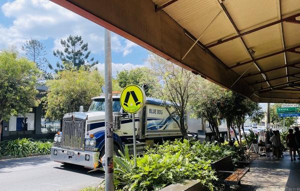A procession of B-double trucks racing through the main drag of Bellingen. Al fresco eating is literally done behind numerous exhaust pipes.