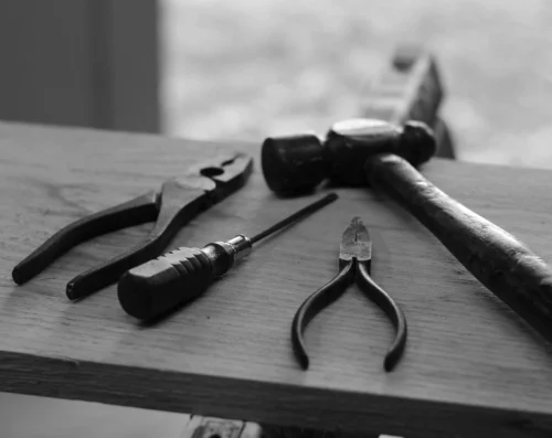 Schwarz-weiß-Bild von einigen Zangen und einem Hammer auf einem Brett.
