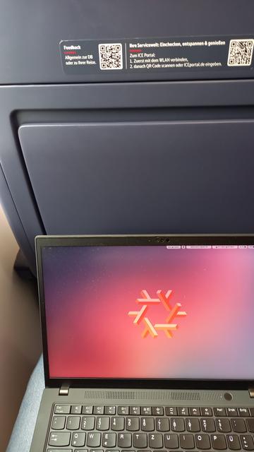 Laptop with NixOS logo background, and train seat of DB ICE.