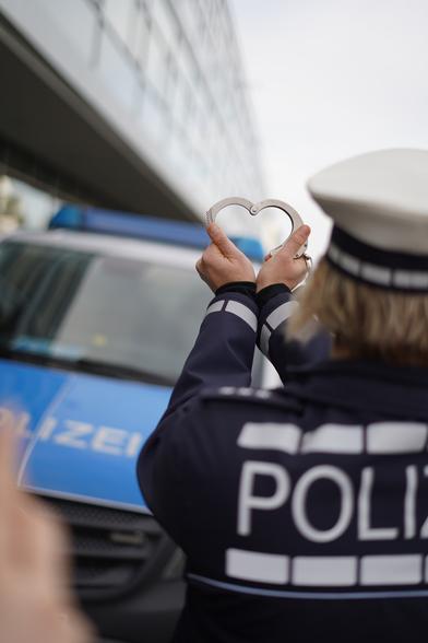 Polizeibeamtin formt ein Herz mit einer Handschließe