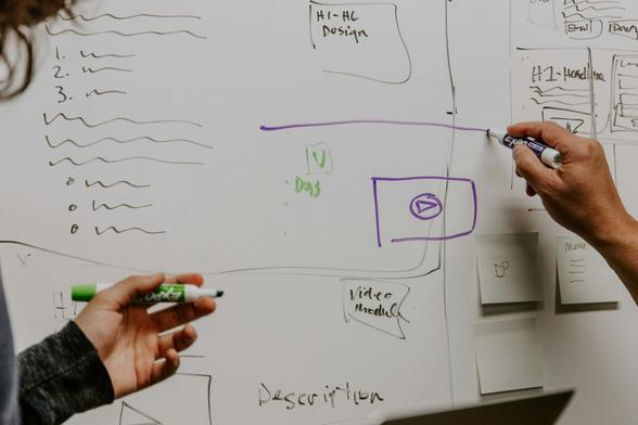 Biała tablica z rysunkami i schematami. Źródło: https://unsplash.com/photos/two-people-drawing-on-whiteboard-26MJGnCM0Wc