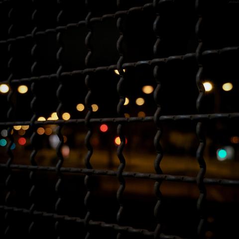 Metallgitter mit glitzernden Lichtpunkten als Bokeh dazwischen