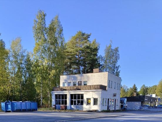 Vanha huoltoasema kuvartuna etelästä. Vieressä sininen roskalava.