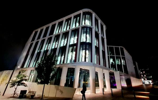 A modern university building photographed at night.