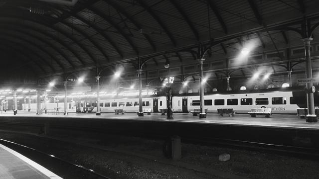 Looking across several platforms and tracks at night towards a local commuter train in Newcastle Station
