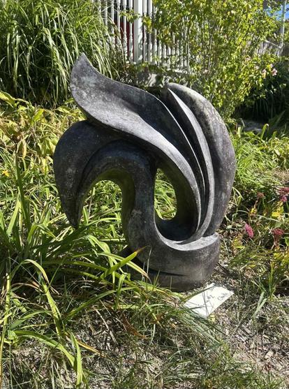 Une sculpture extérieure abstraite en pierre naturelle noire. La forme ressemble à un cygne.