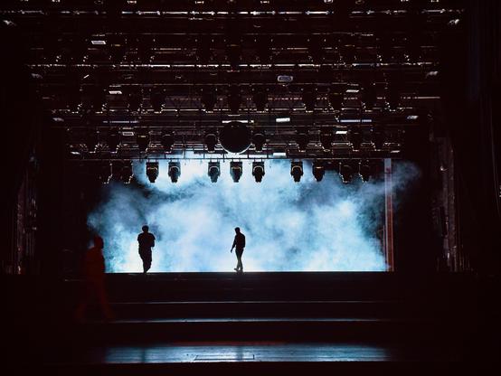 Photo of a proscenium stage with a wall backlit of fog.