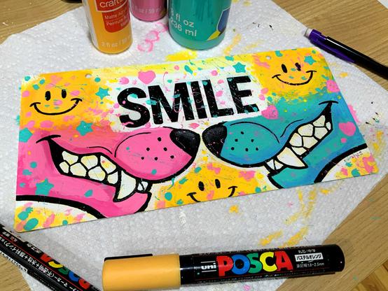 Acrylic paintover of a plastic "smile your on camera" sign featuring a pink and blue grinning maw on each side
