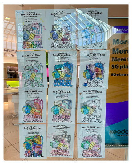 Multiple flyers featuring children’s drawings advertising a "Back to School Sale" with 'PureFibre Internet' offers are displayed on a glass window. The flyers are colorful and include images of school-related items like books and pencils. Reflected in the window is the interior of a mall, showing architectural details of the ceiling and other stores in the background. Some promotional text for mobile phone plans is also visible on the glass.
