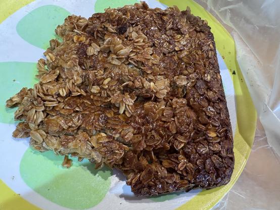 Irregularly shaped, formerly square, oat confection on a green and yellow plate.