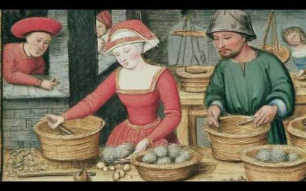 Painting of medieval man and woman at a table with crockery bowls,  dying balls of yarn, seems like. Someone (young male apprentice?) peering in from a deep brick-laid window on the left, set in the interior of a brick and stone building. This all speaks to the power of guilds back in the day. Other people can be seen working in the background, so this was probably the "factory," really more of an atelier.