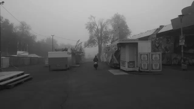Fahrradfahrer auf einem morgendlichen Kirmesplatz im Nebel