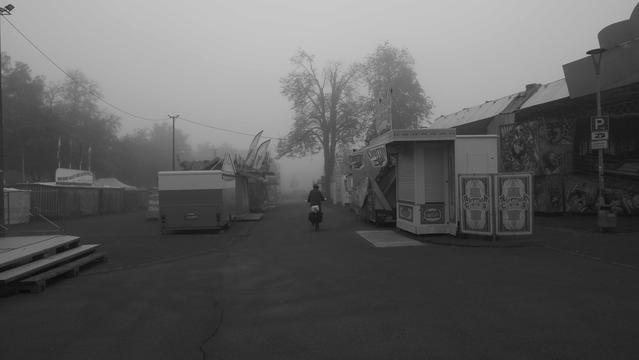 Fahrradfahrer auf einem morgendlichen Kirmesplatz im Nebel