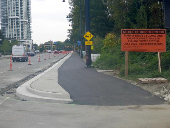 Multi-use path construction. Path has been paved, but road next to the path requires pavement. Looking east along Marine Drive from near the north end of the Lions Gate Bridge.