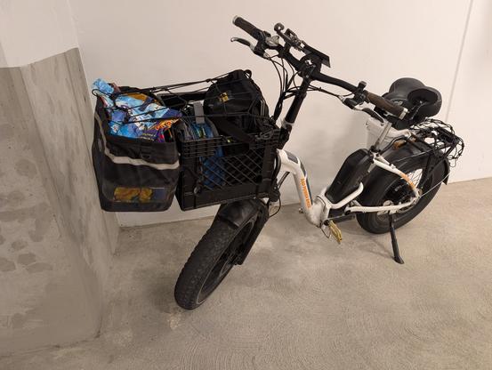 Radpower mini ebike with a front rack, crate, and a painter hanging off the front of the crate for extra carrying capacity