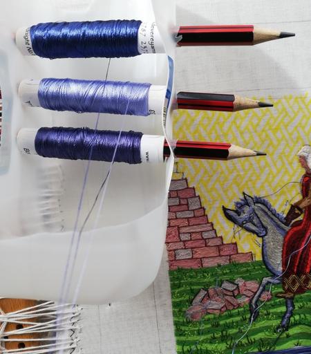 Spool holder improvised with a plastic milk bottle and some pencils, lying on the Aethelflaed embroidery.