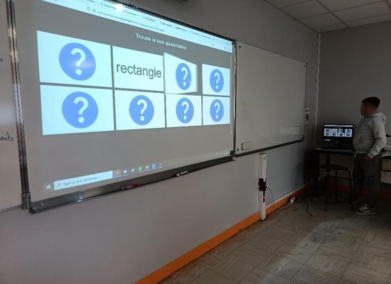 Élève ce tableau manipulant la souris sur un ordinateur envoie un vidéoprojecteur projeté sur le tableau un memory numérique une carte est retournée il est écrit rectangle une autre carte est en train de se retourner.