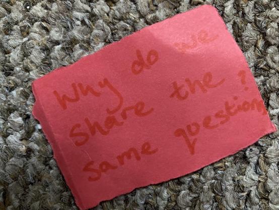 Small red card with ‘why do we share the same questions?’ handwritten on it