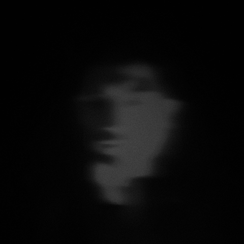 A heavily distorted, blurry, black-and-white photo of myself. The camera captures my face as I look down and to the left of it. There is a heavy motion blur effect on the left side of my face.