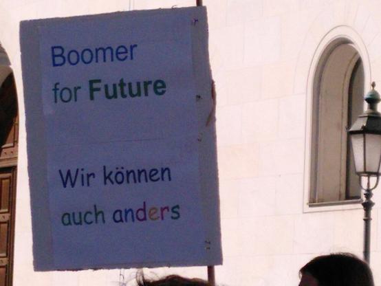 Demo-Schild vor altem Gebäude (am Sophie-Scholl-Platz in München): "Boomer for Future. Wir können auch anders"